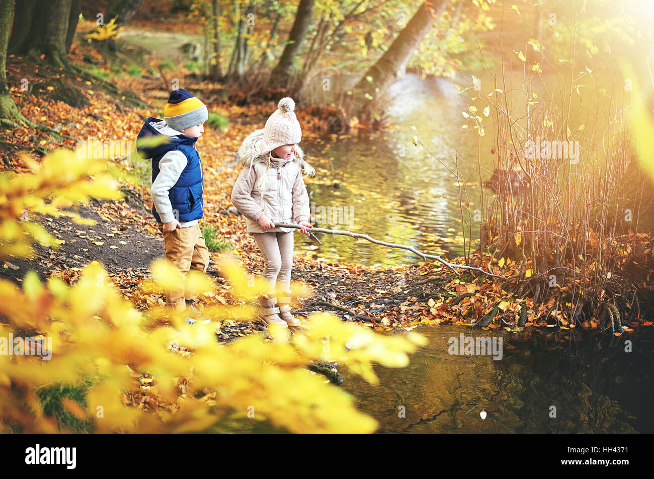 I due ragazzi in piedi vicino al laghetto in autunno foresta. All'aperto orizzontale shot Foto Stock