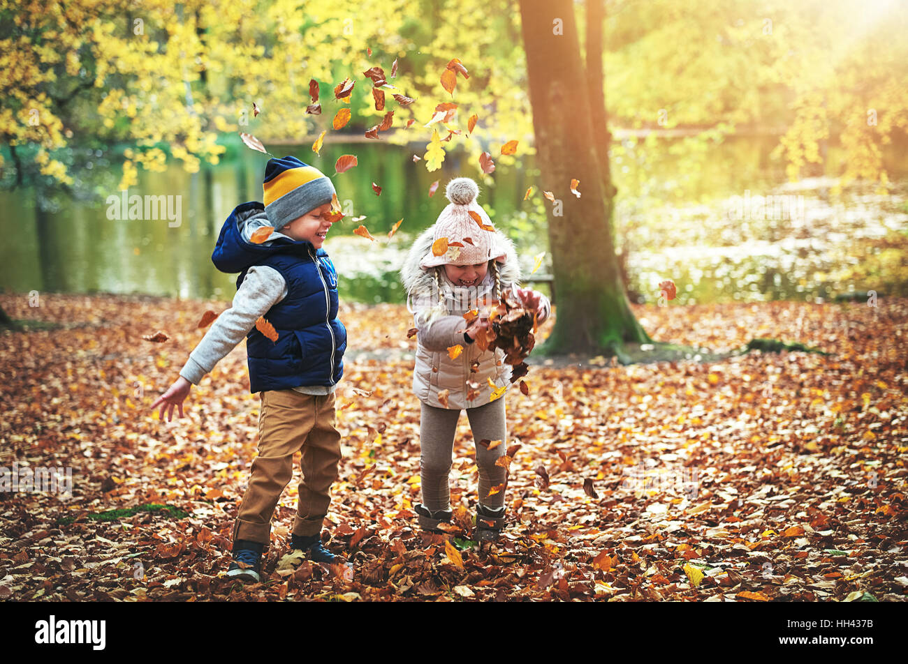 Kids holding foglie gialle nella foresta. All'aperto orizzontale shot Foto Stock