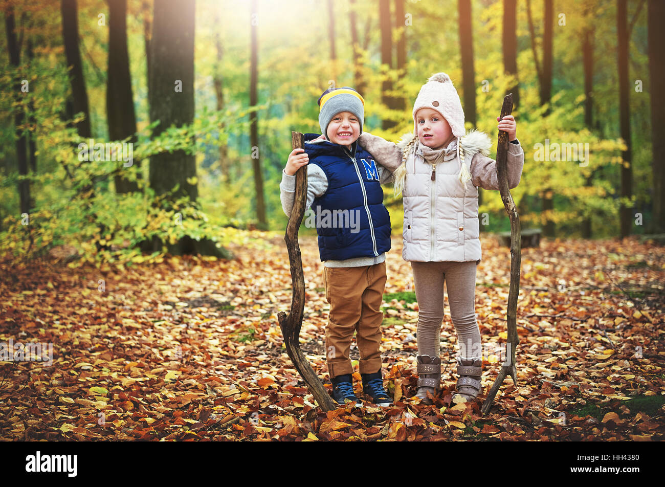 Contenti i bambini in posa con filiali in foresta. All'aperto orizzontale shot Foto Stock