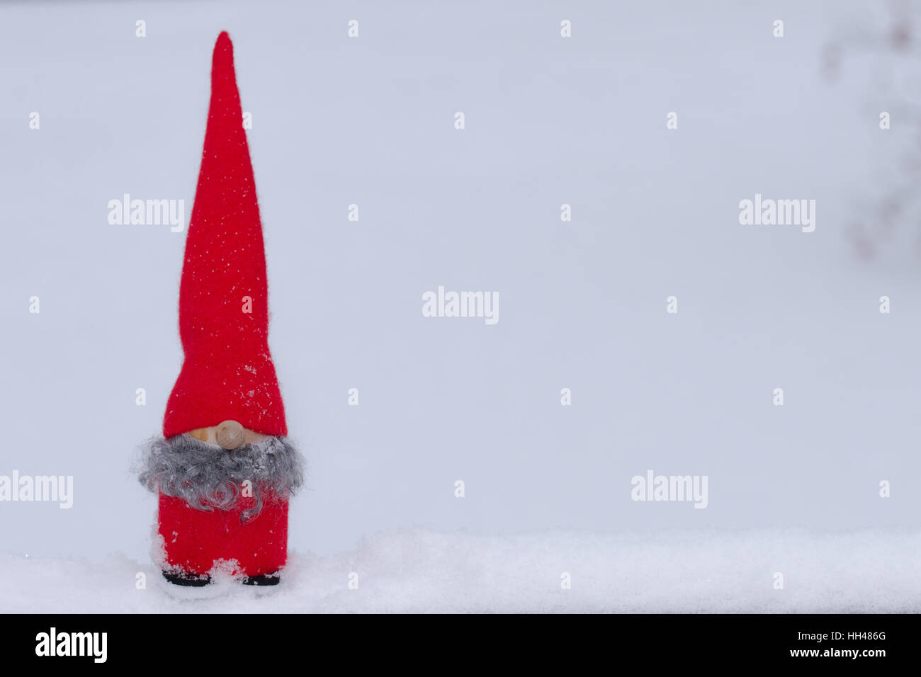 Un giocoso gnome si siede nella neve vera con una stanza per la copia o il testo Foto Stock