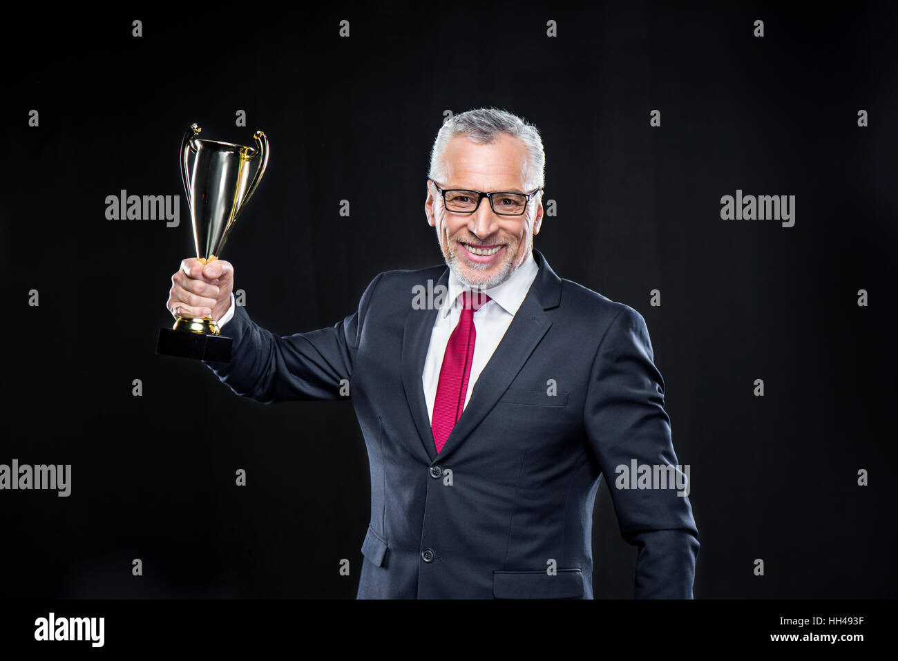 Felice coppia imprenditore tenendo award cup su nero Foto Stock
