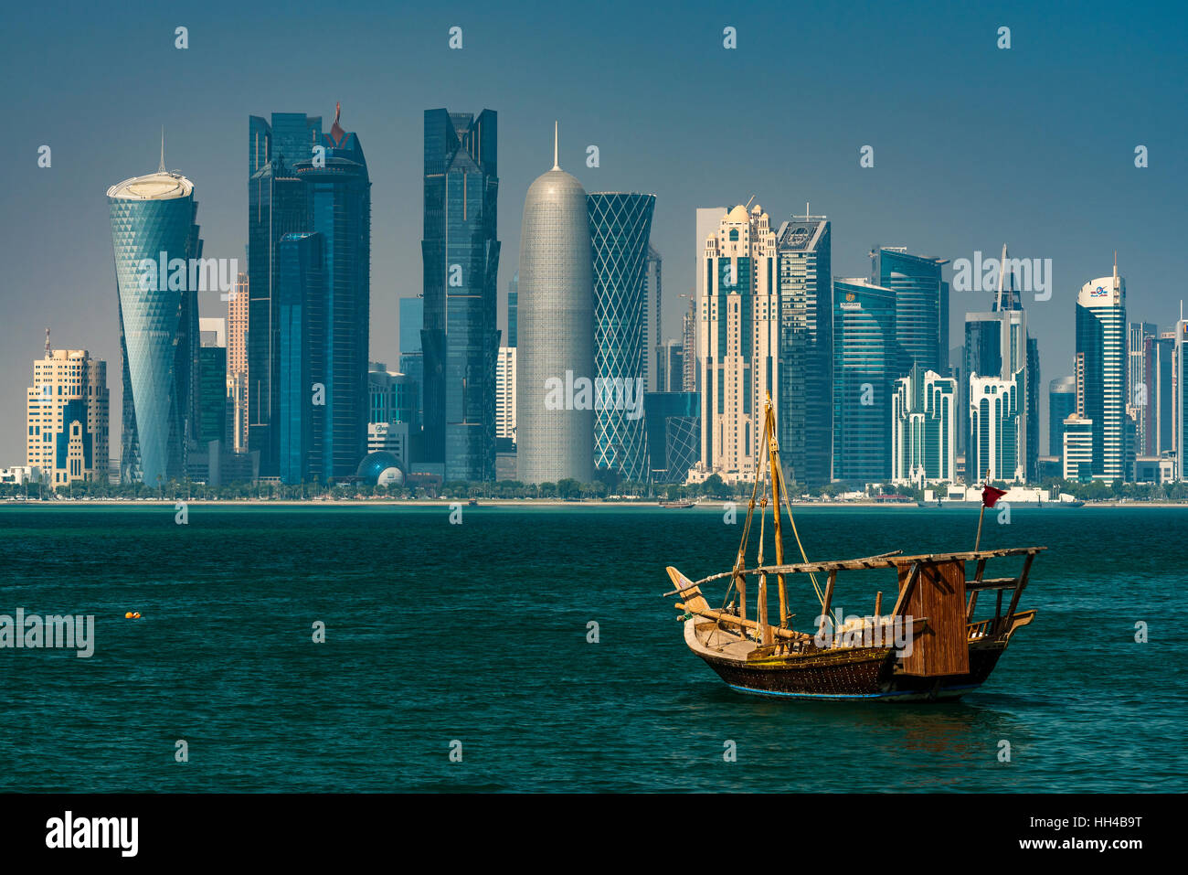 Dhow tradizionale imbarcazione a vela con il settore finanziario skyline dietro, Doha, Qatar Foto Stock