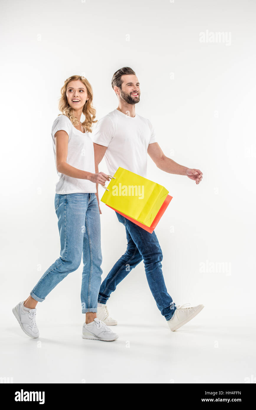 Sorridente coppia giovane a piedi con le borse della spesa su bianco Foto Stock