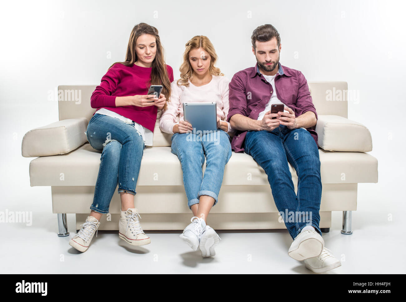 Concentrate i giovani seduti sul divano e utilizzando dispositivi digitali Foto Stock