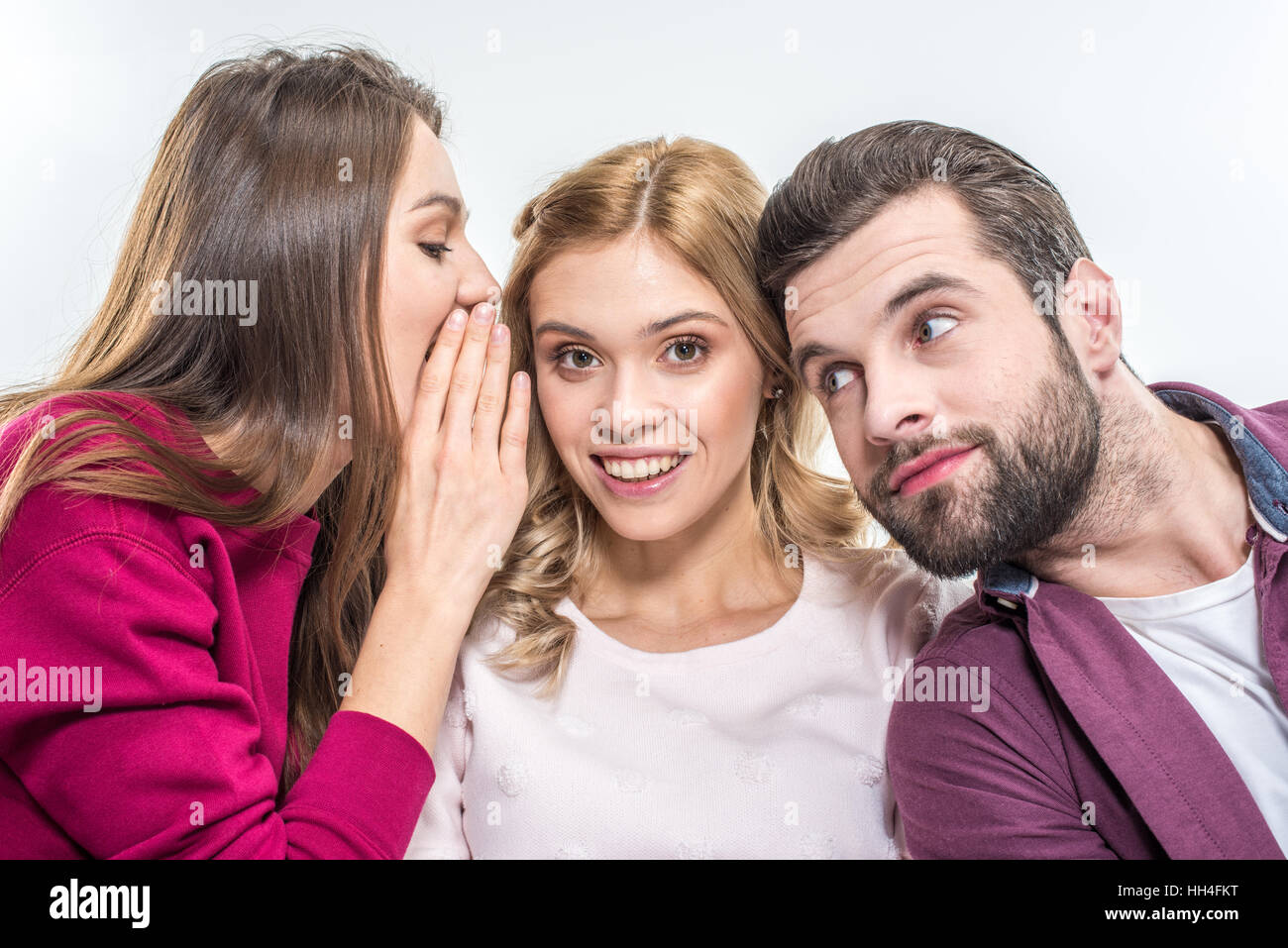 Giovani amici whispering su bianco Foto Stock