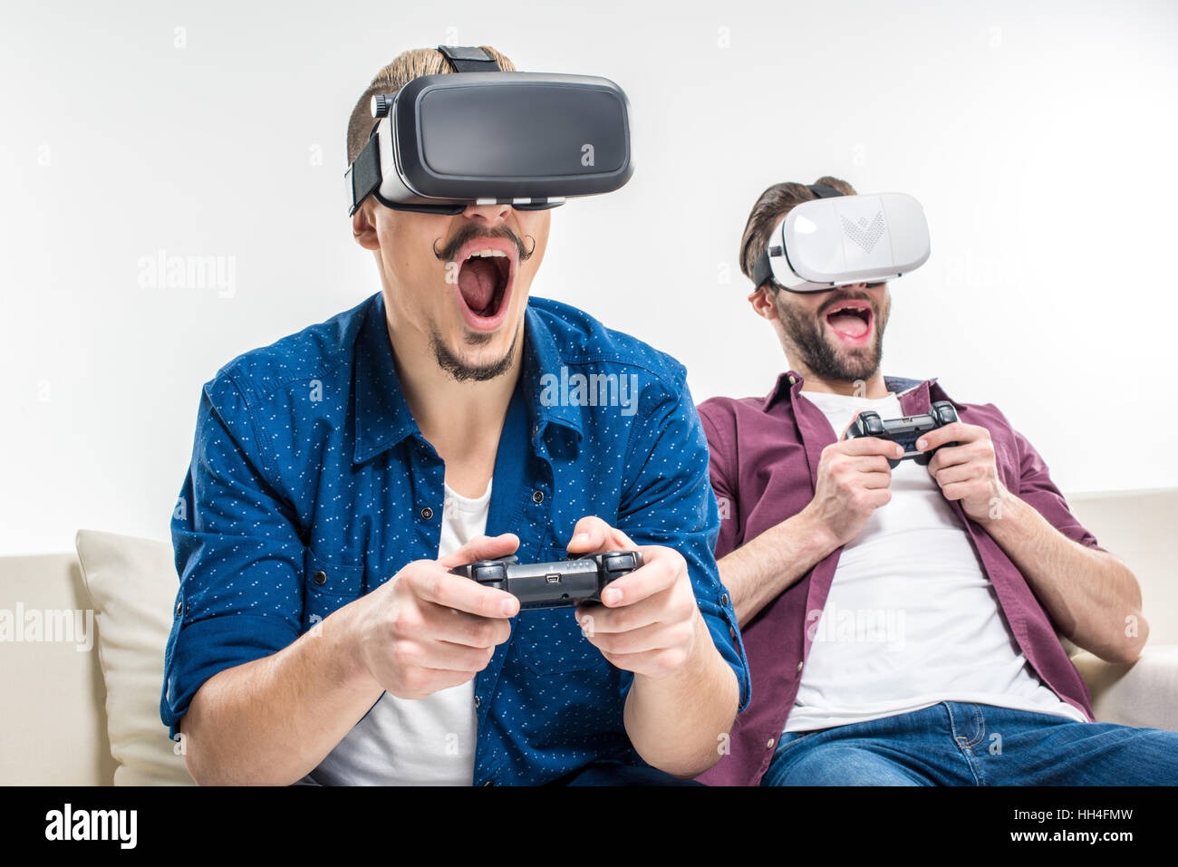 Maschio eccitato amici per giocare con i videogiochi in realtà virtuale di cuffie Foto Stock