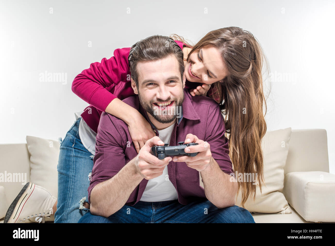 Donna sorridente abbracciando giovane uomo barbuto giocando con joystick Foto Stock