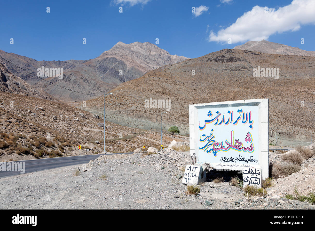 Corsa su strada attraverso le montagne intorno a Kerman, Iran. La Propaganda cartello stradale : " Non vi è nulla di più prezioso di martirio' - leader supremo Foto Stock