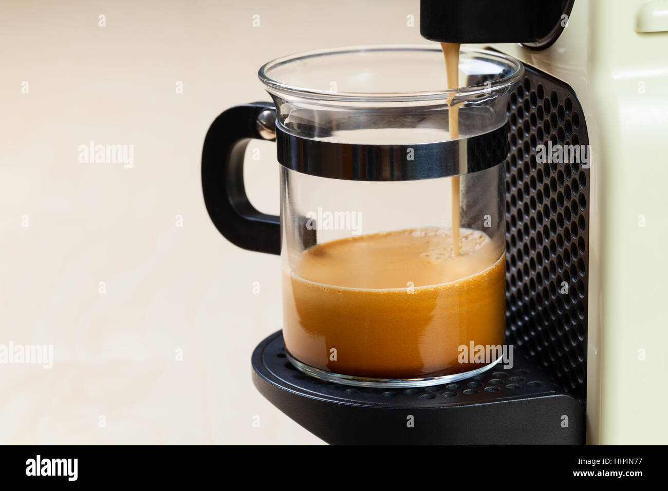 A singolo che serve caffe macchina eroga caffè espresso in un bicchiere di vetro Foto Stock