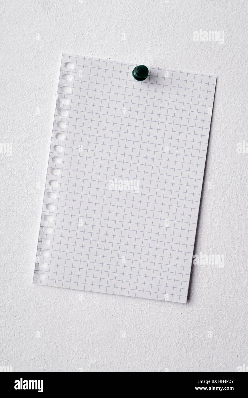 Primo piano di un pezzo di carta è imperniata in un muro bianco con un perno di spinta Foto Stock