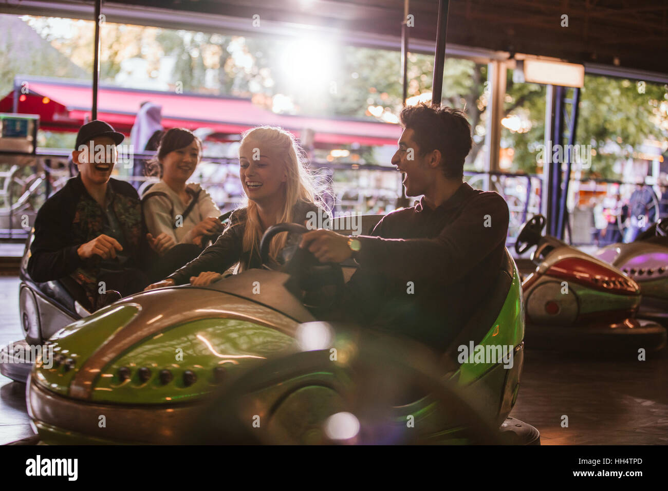Gruppo di amici che si divertono sull bumper car ride nel parco di divertimenti. Giovane uomo e donna per divertirsi con il paraurti di automobili. Foto Stock