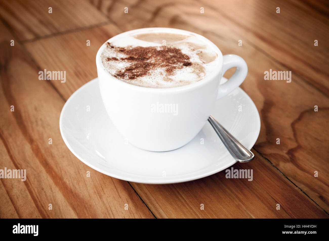 Il Cappuccino. Tazza di caffè con schiuma di latte e cannella sorge su di un tavolo di legno Foto Stock