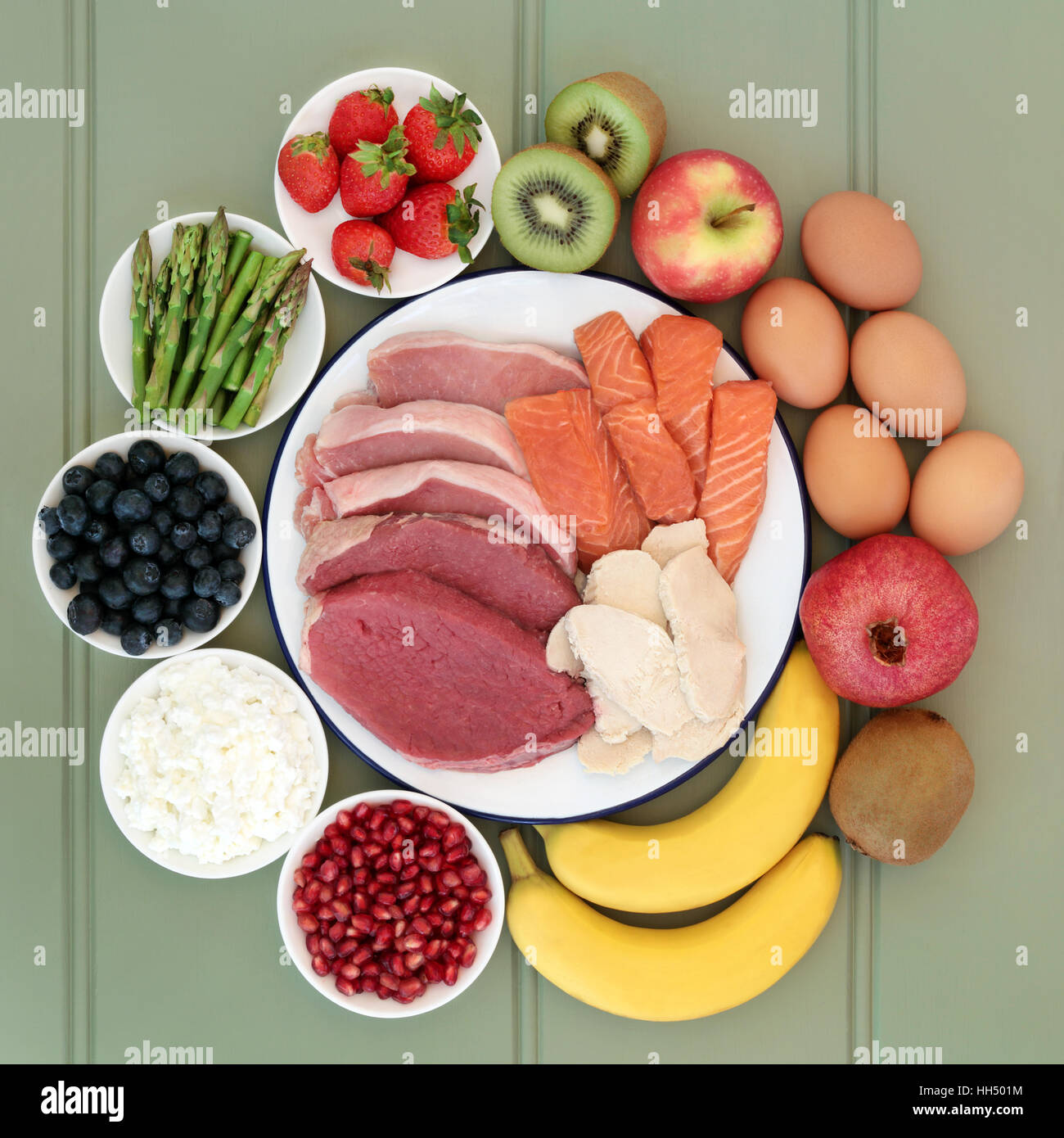 Della salute alimentare per i costruttori del corpo con carne, pesce, frutta e prodotti lattiero caseari su legno verde dello sfondo. Foto Stock