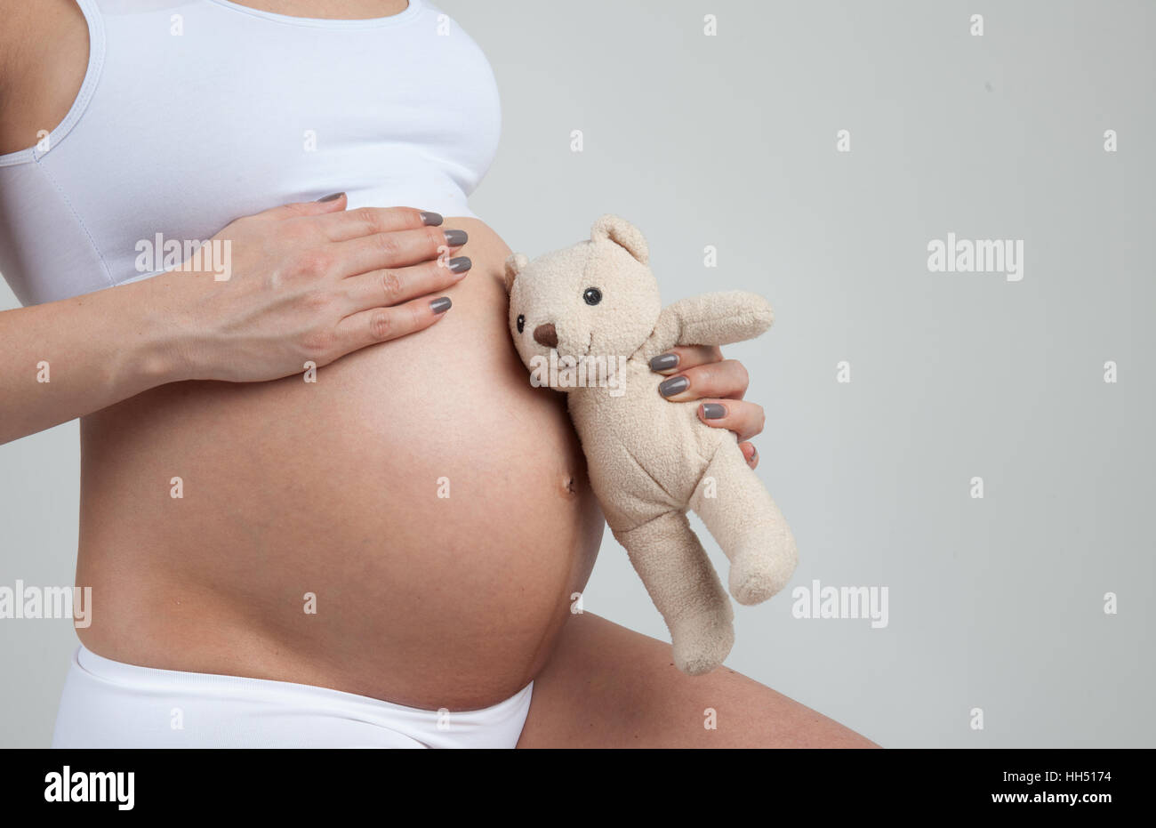 Piccolo Orso ascolta per il ventre di una donna in stato di gravidanza Foto Stock