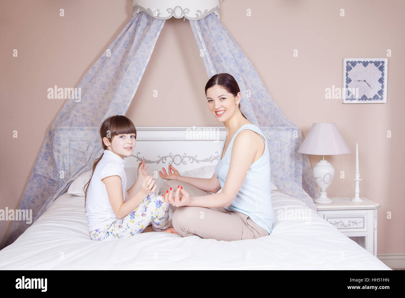 Felice madre e figlia meditando e sorridere mentre in seduta yoga pone sul letto di casa. Studio shot. Foto Stock