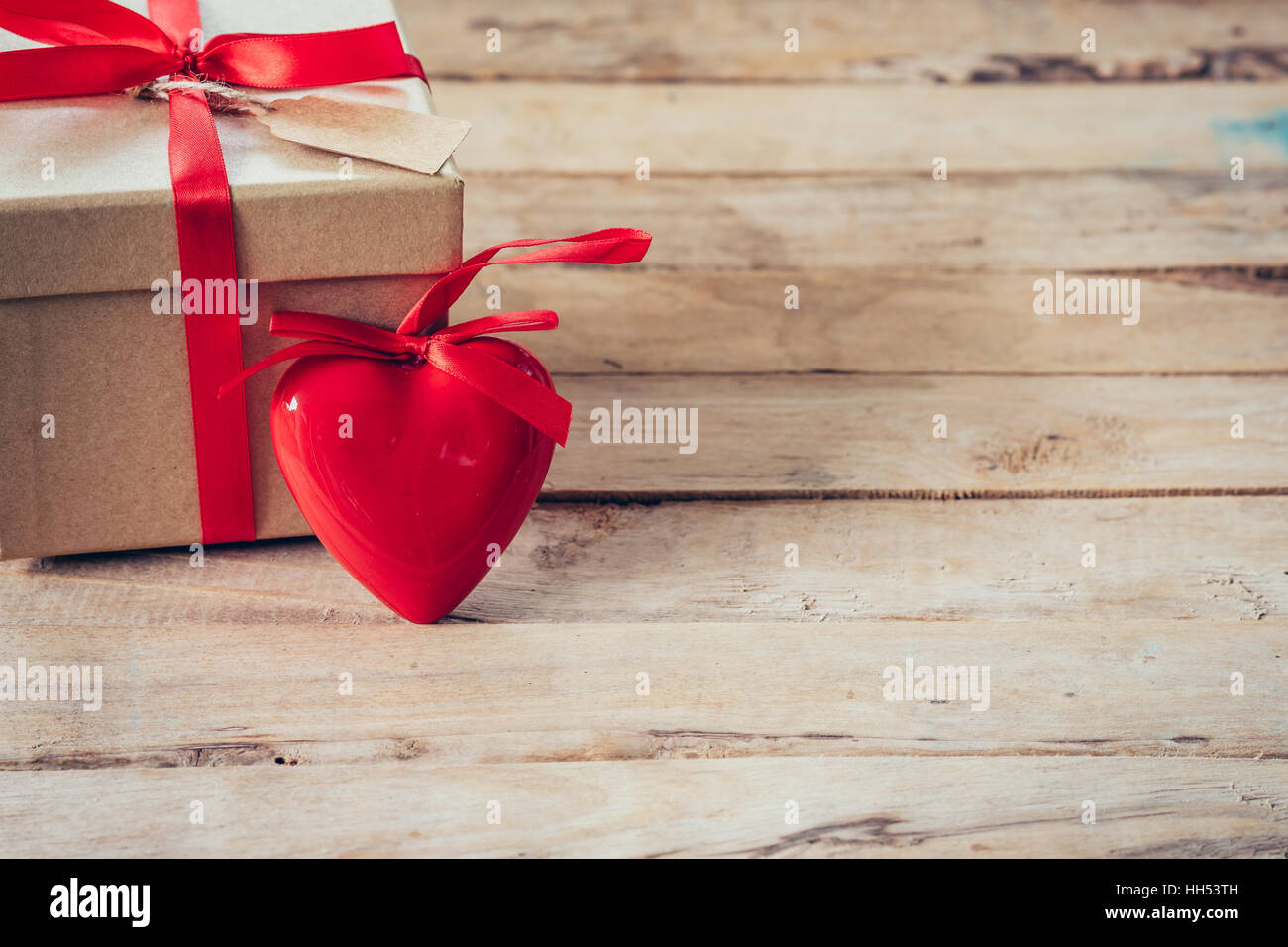 Confezione regalo e cuore rosso sul tavolo di legno con uno spazio Foto Stock