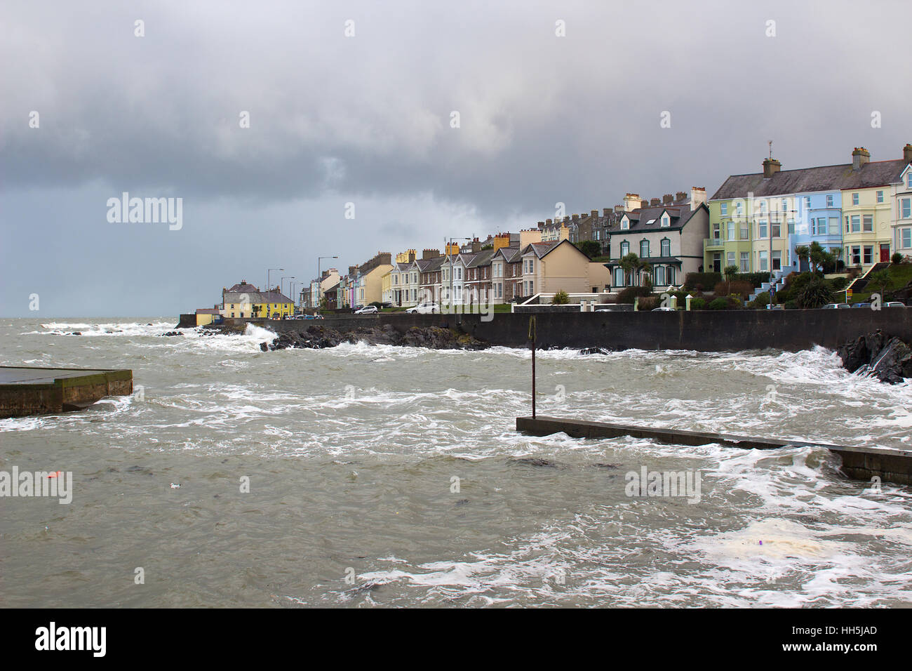 Una tempesta di neve sul mare irlandese batte un piccolo porto entrata con forte vento e onde Foto Stock