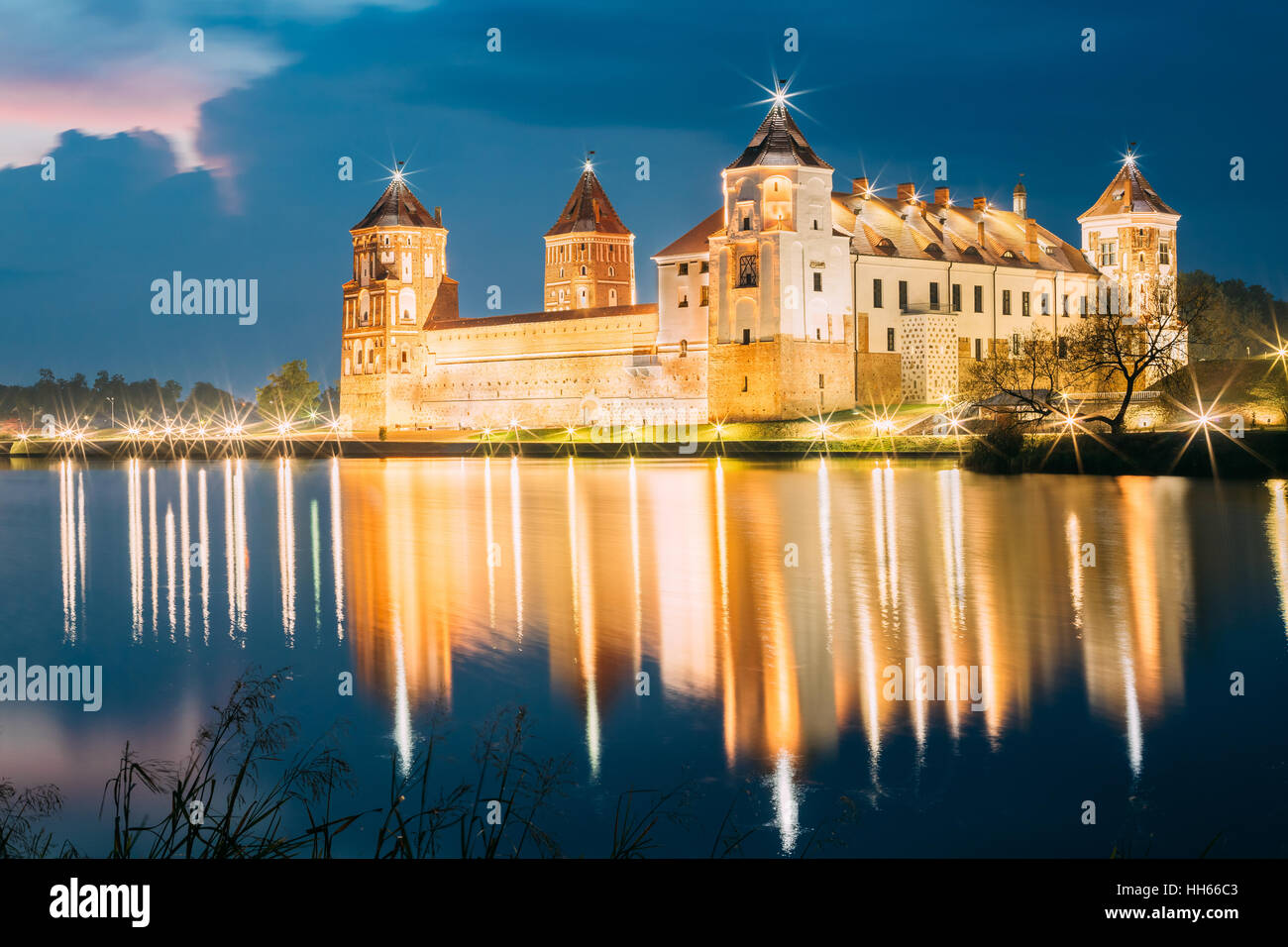 Mir, Bielorussia. Una vista pittoresca del complesso del Castello di Mir In brillante illuminazione serale con candelette di riflessioni sul lago di acqua. Famoso punto di riferimento, antica Gothi Foto Stock