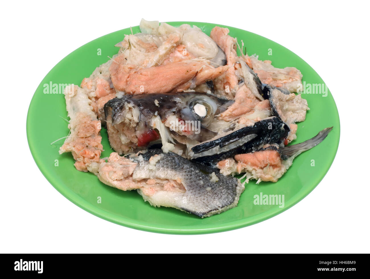 Le ossa, la testa e la pelle di un semplice salmone bollito giacciono su un verde piastra ceramica. Isolato su bianco closeup shot Foto Stock