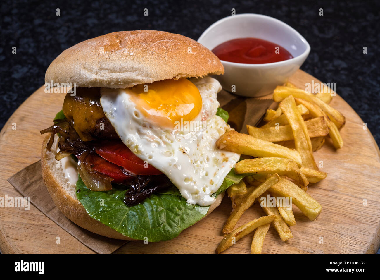 Formaggio di casa burger con pane, uova, patatine e salsa sul piatto di legno Foto Stock