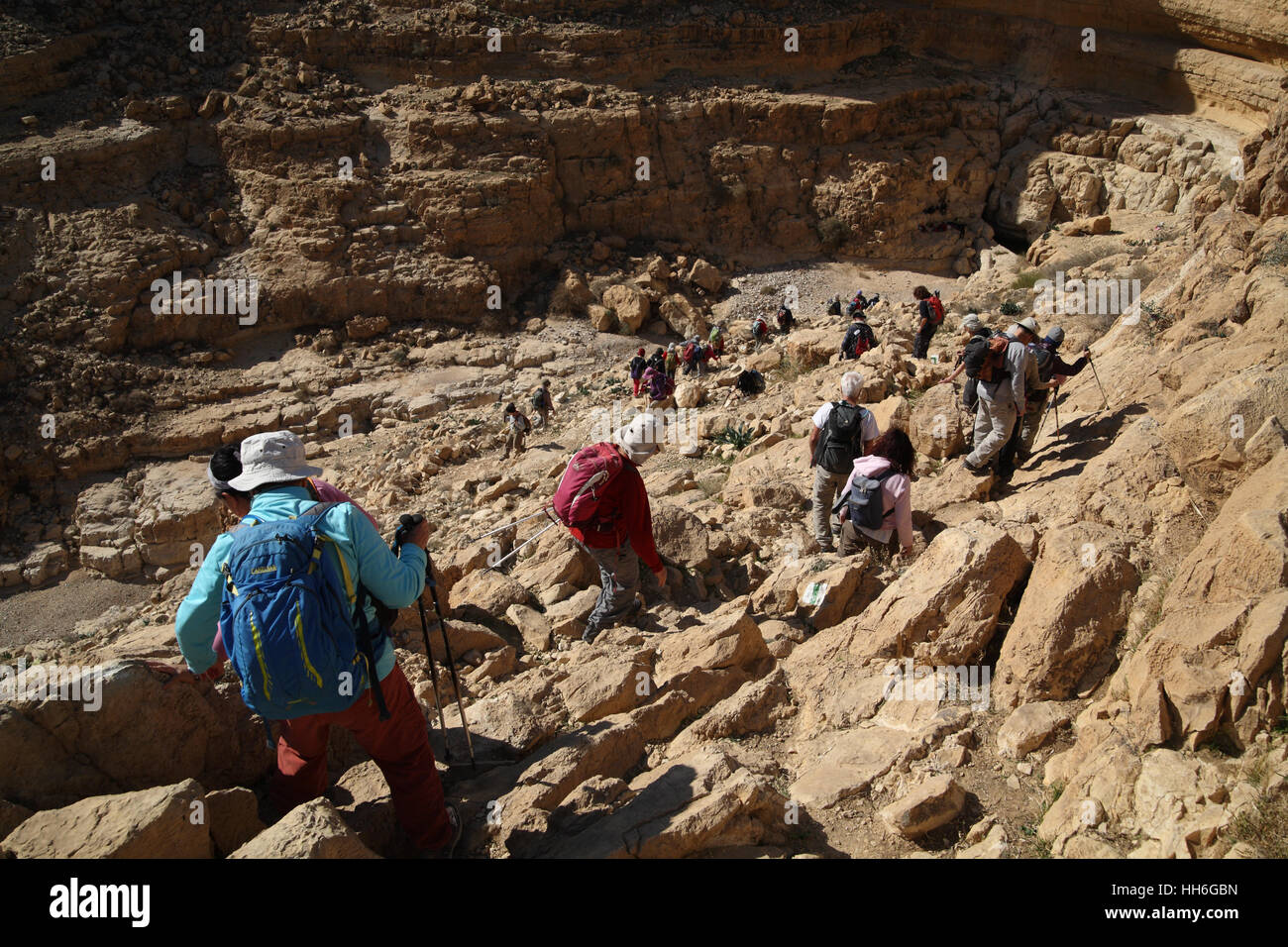 Senior Citizen gli escursionisti sono attentamente scendendo un trekking nel canyon di Nachal o Nahal Kina, il Deserto della Giudea, Israele. Foto Stock
