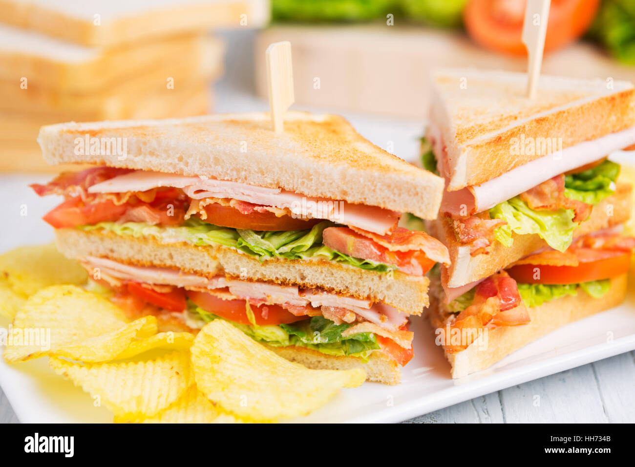 Un club sandwich su un tavolo rustico in condizioni di luce intensa. Foto Stock
