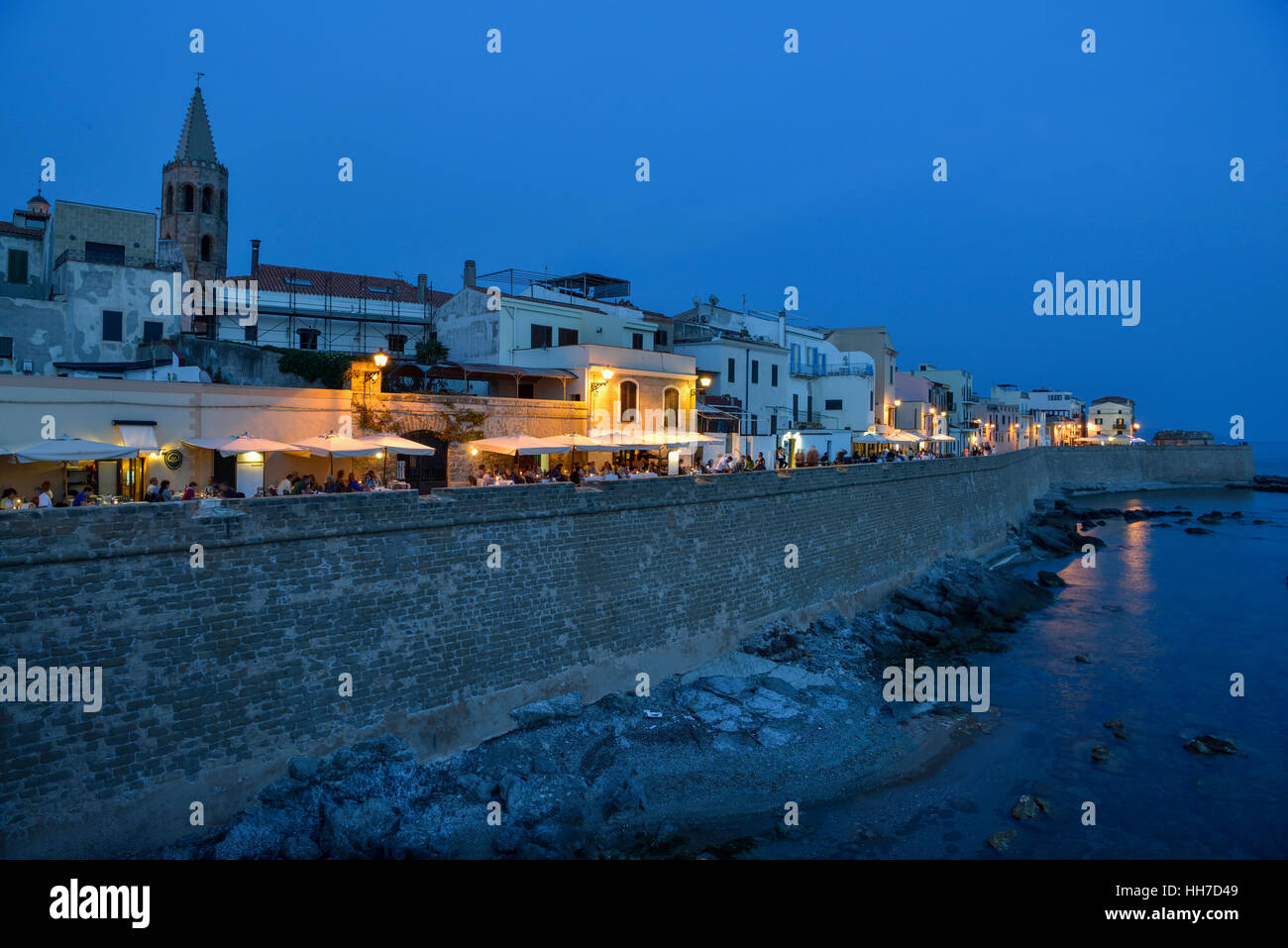 Fila di case, ristoranti e le mura cittadine, crepuscolo, Alghero, provincia di Sassari, Sardegna, Italia Foto Stock