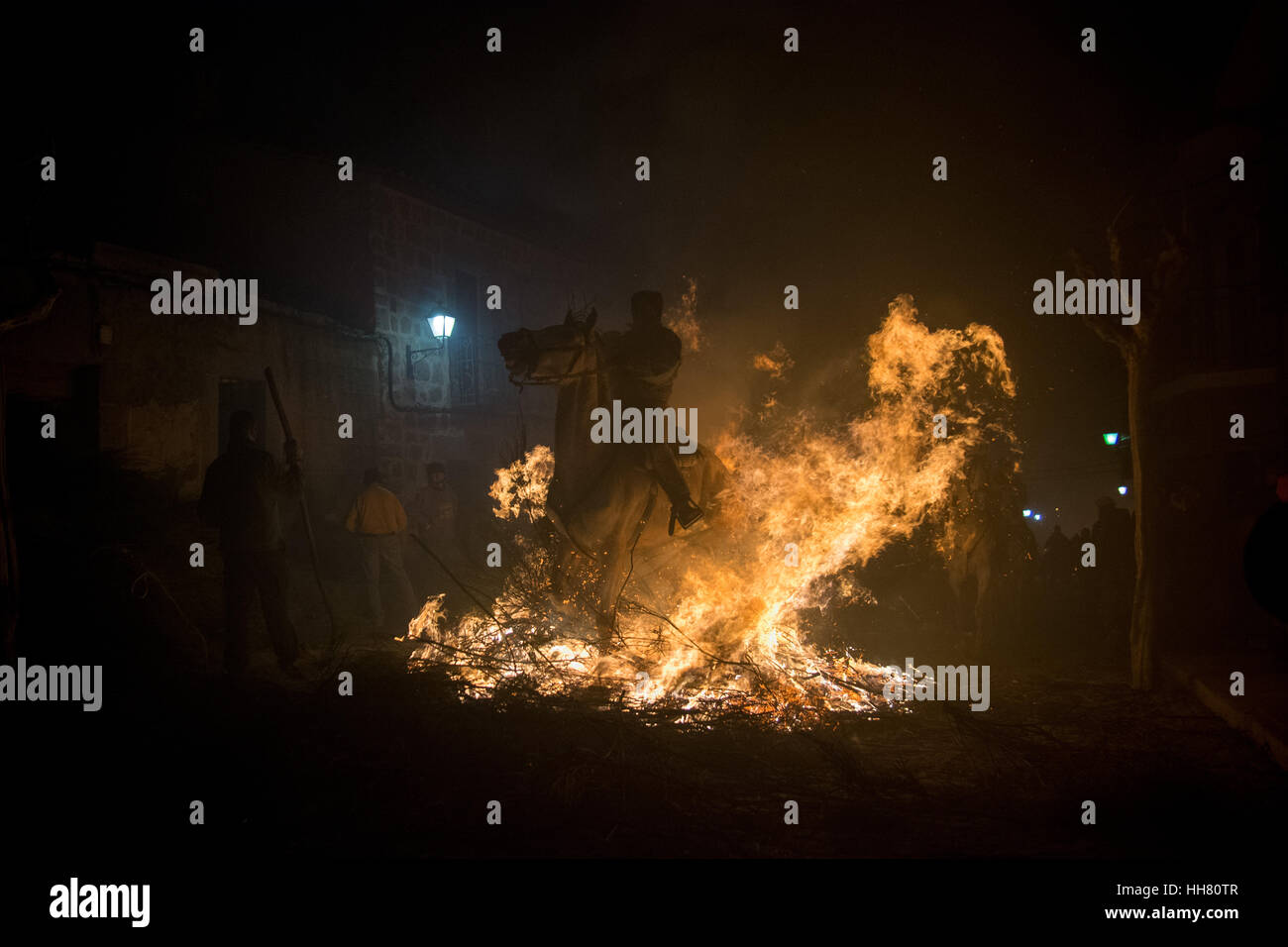 San Bartolome de Pinares, Spagna. 16 gennaio, 2017. Un uomo che cavalca un cavallo attraverso un falò durante 'Las Luminarias' Festival di Sant'Antonio Abate, patrono degli animali. Cavalli saltare attraverso i falò la notte prima del giorno di onorare gli animali. La tradizione è destinata a purificare e a proteggere gli animali. Credito: Marcos del Mazo/Alamy Live News Foto Stock