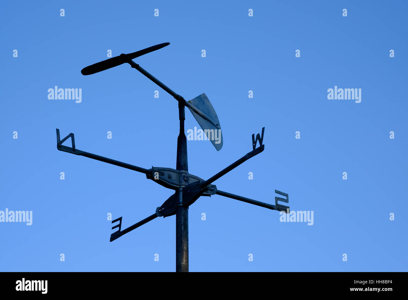 Rustico banderuola, parziale silhouette, contro un cielo blu chiaro, che mostra la direzione del vento del nord dal nord-ovest Foto Stock