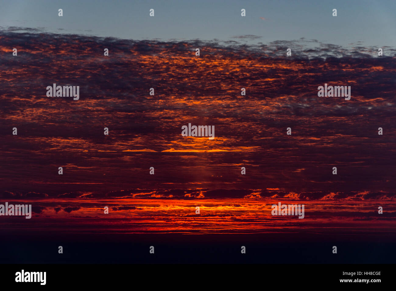 Luce rossa sulla parte inferiore delle nuvole al tramonto sul mare del Nord sulla costa orientale dell'Inghilterra. Foto Stock