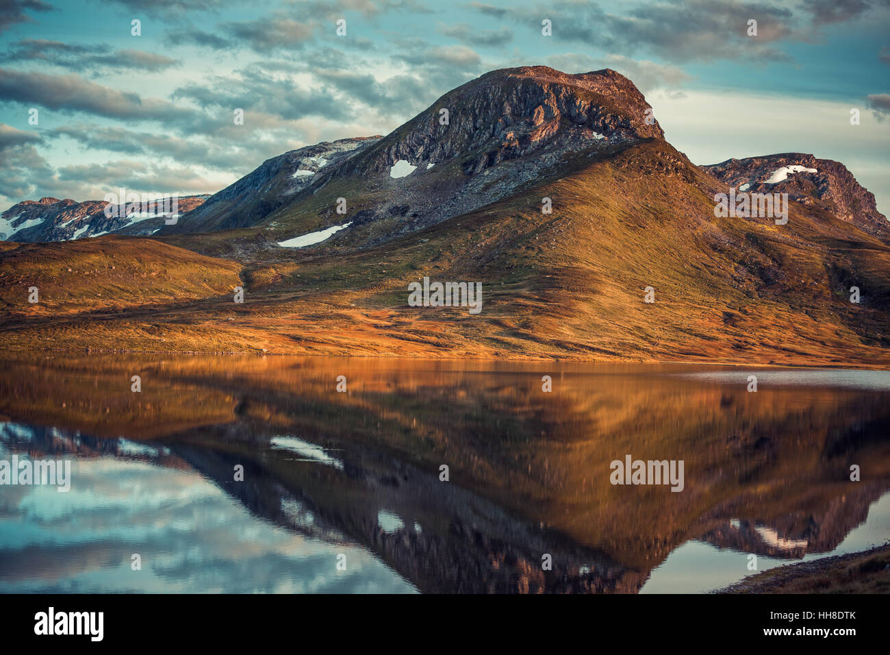Le montagne con la riflessione nel lago in Norvegia. Autunno rosso stile pellicola a colori. Foto Stock