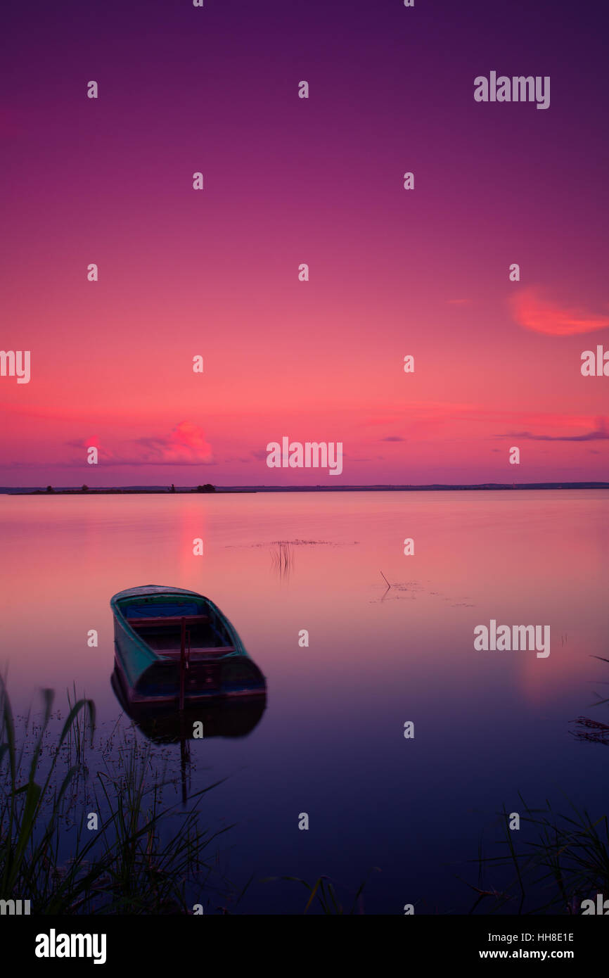 Il lago di paesaggio con barca. Crepuscolo rosso colori. Foto Stock