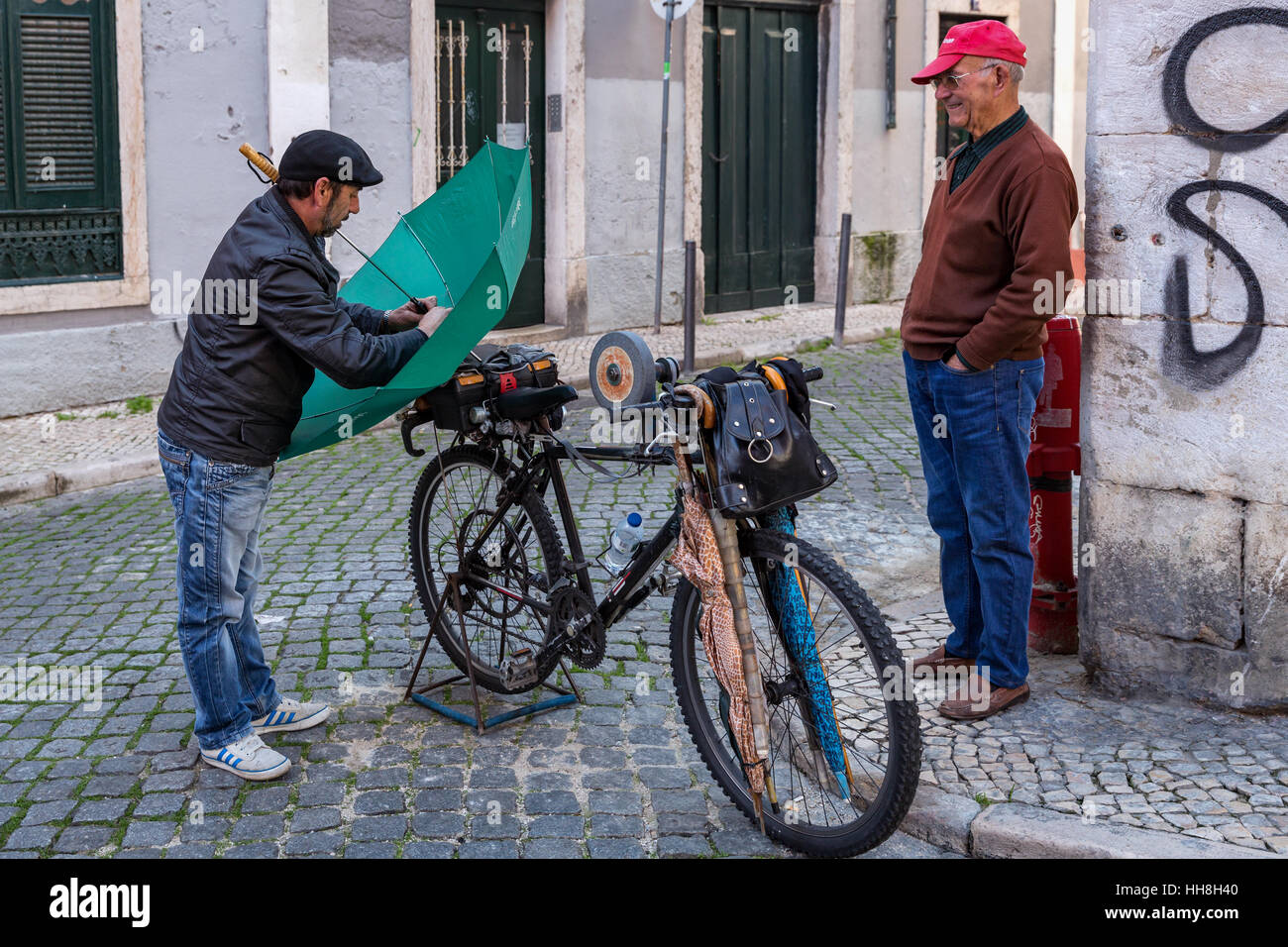 Un coltello di strada-uomo di affilatura delle riparazioni di un ombrello, Lisbona, Portogallo Foto Stock