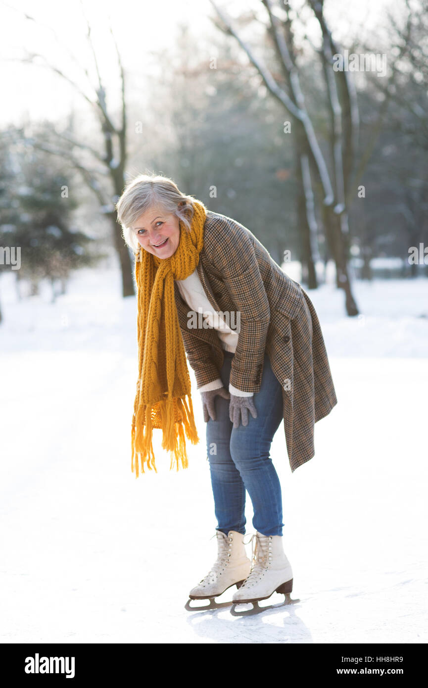 Senior donna in inverno pieno di sole natura pattinaggio sul ghiaccio. Foto Stock