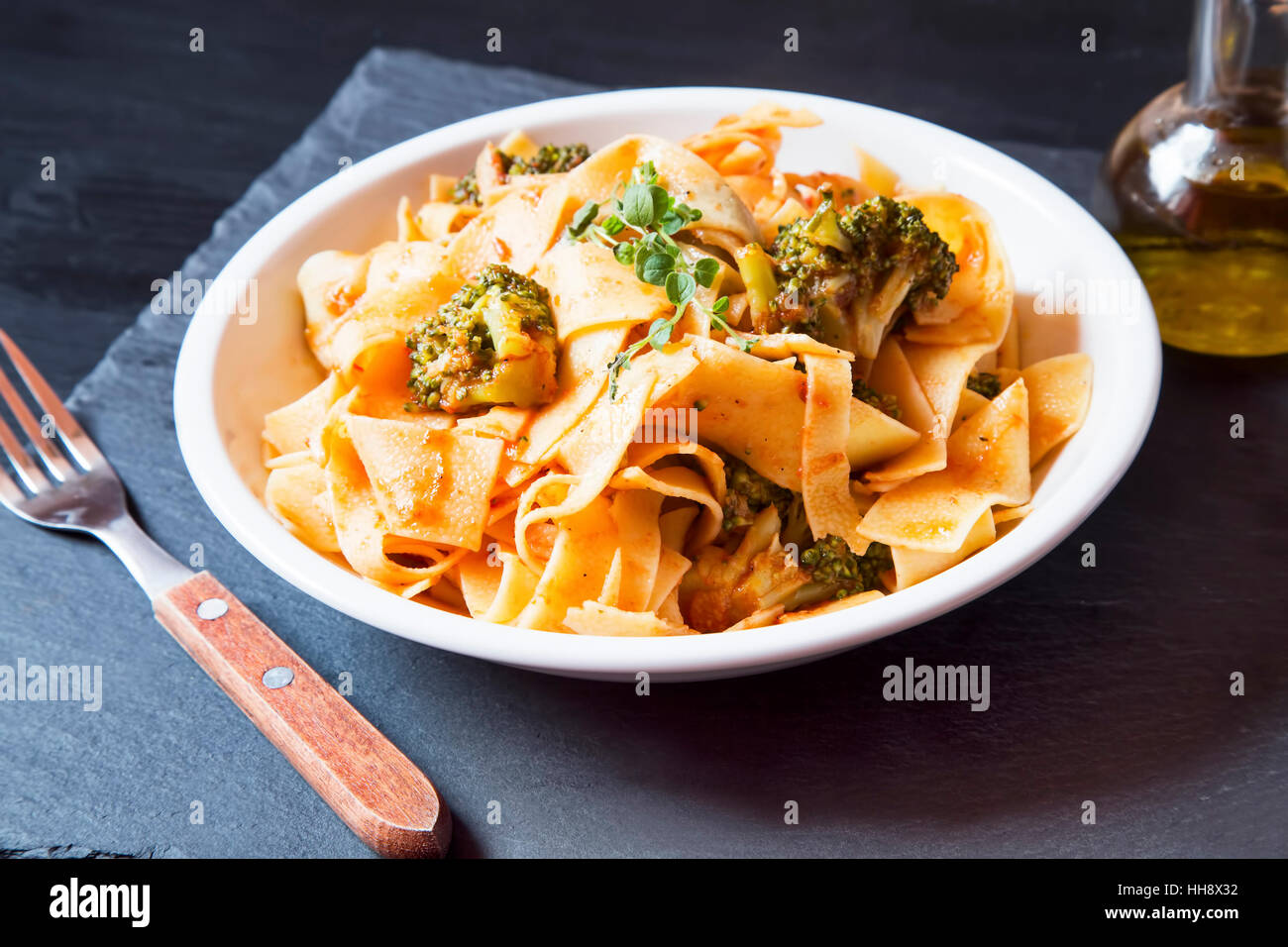 Tagliatelle con broccoli e salsa di pomodoro sulla piastra bianca con origano condimento alle erbe Foto Stock