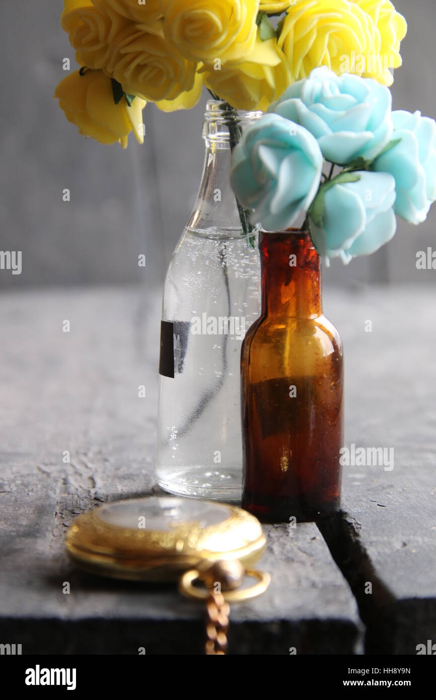 Fiori in bottiglie rurale sul tavolo di legno. Foto Stock