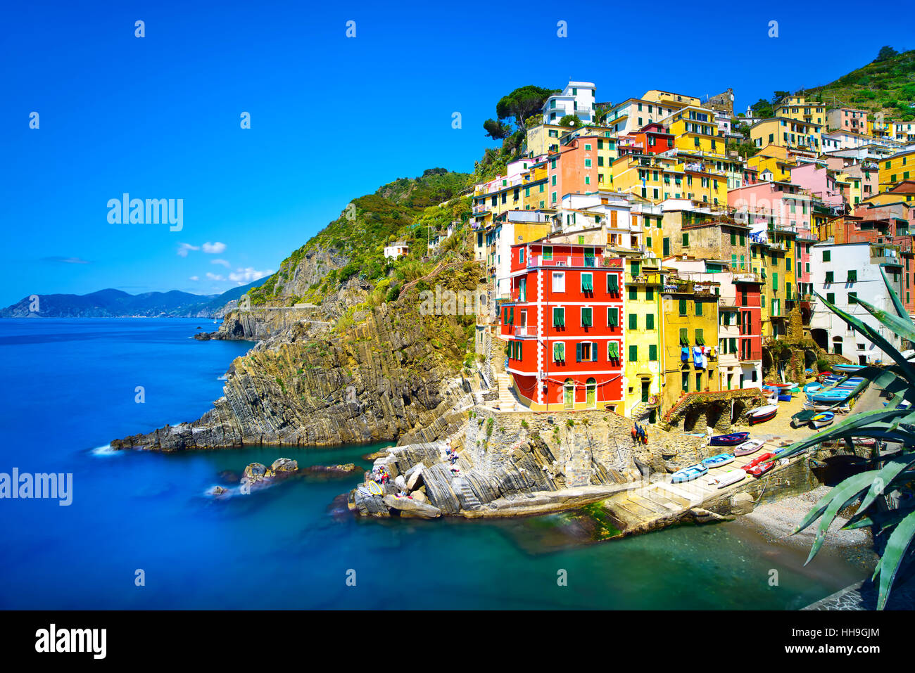 Riomaggiore villaggio sulla scogliera di rocce e mare al tramonto., Seascape in cinque terre, il Parco Nazionale delle Cinque Terre Liguria Italia Europa. Esposizione lunga Foto Stock