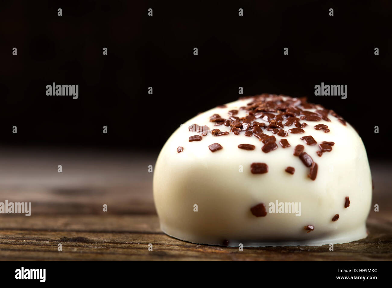 Il cioccolato bianco candy con piccoli pezzi di cioccolato scuro su uno sfondo di legno Foto Stock
