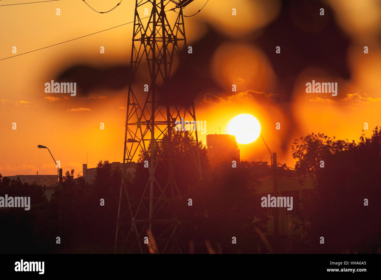 Tramonto su linee elettriche sul traliccio in una città di forme Foto Stock
