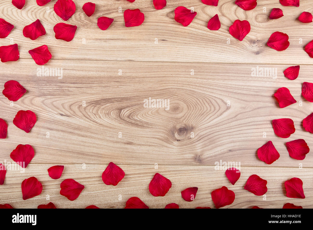 In tessuto rosso petali di rose con copia spazio nel centro su un sfondo di legno Foto Stock