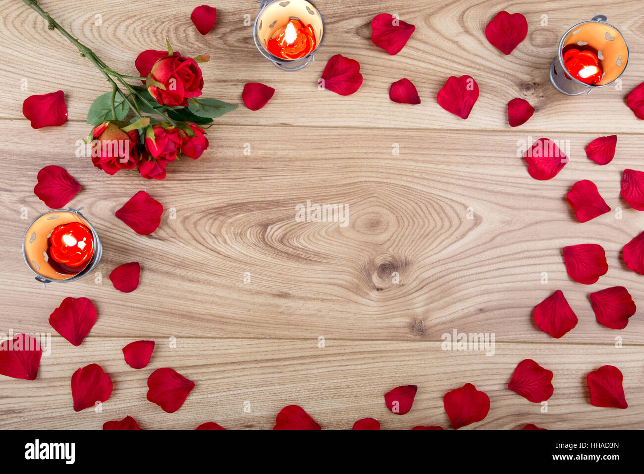 In tessuto rosso rosa e petali di rosa con candela tealight su uno sfondo di legno Foto Stock