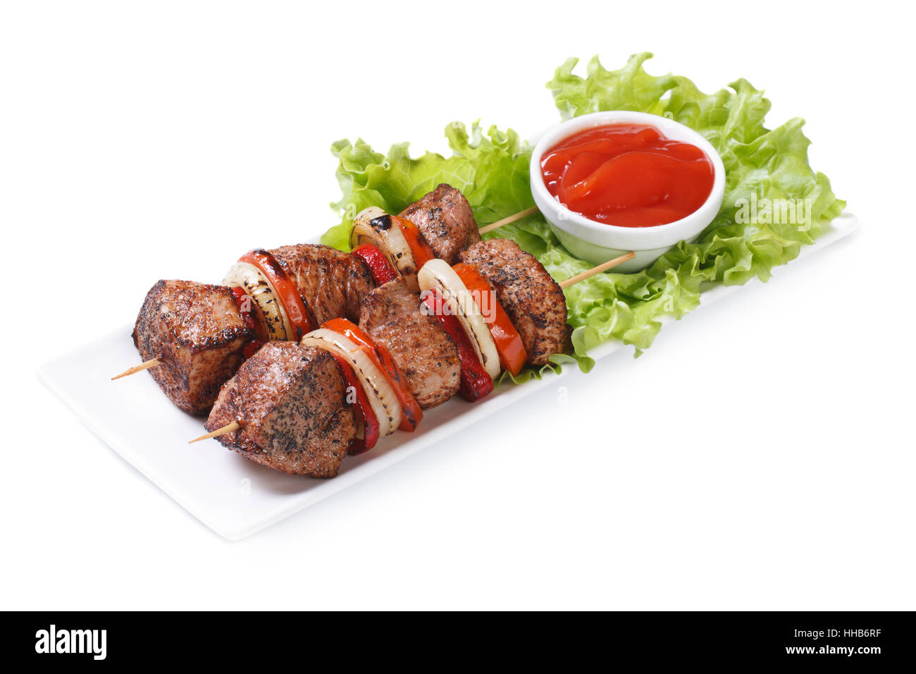 Shish kebab dal maiale con verdure e salsa su una piastra bianca isolata Foto Stock