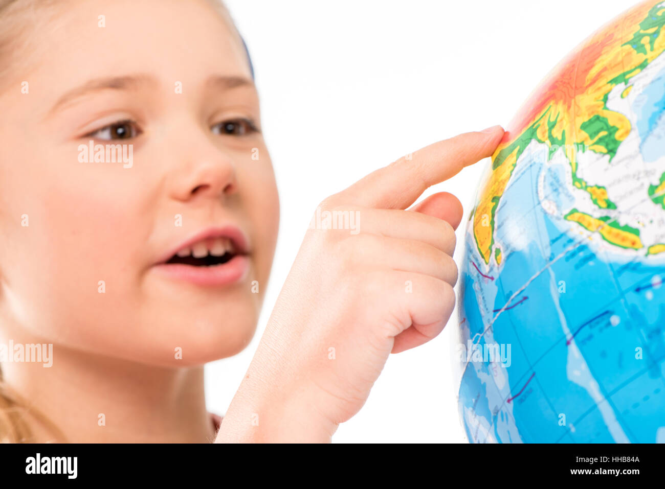 Felice schoolgirl esplorare globe isolato su bianco Foto Stock