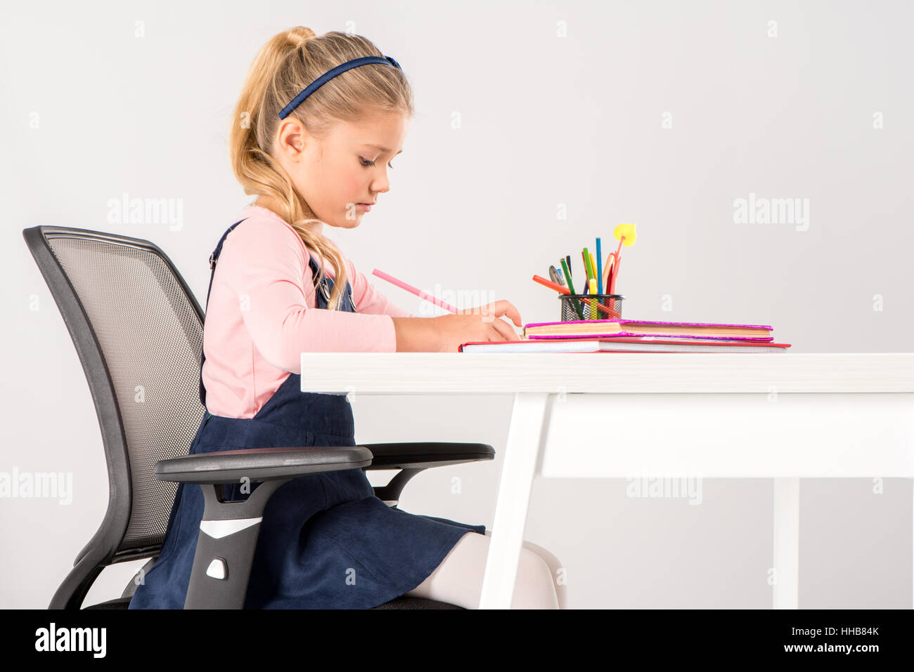 Grave schoolgirl seduto alla scrivania e fare i compiti di scuola Foto Stock