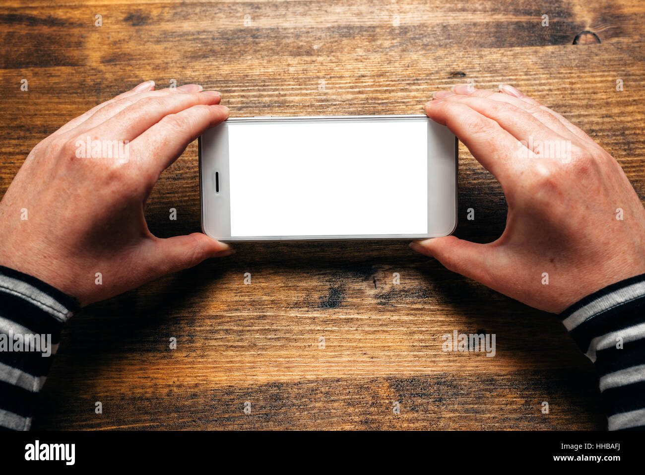 Donna che utilizza smart phone in orizzontale con orientamento orizzontale per lo streaming di filmati o sfogliare foto gallery, schermo vuoto come spazio di copia Foto Stock