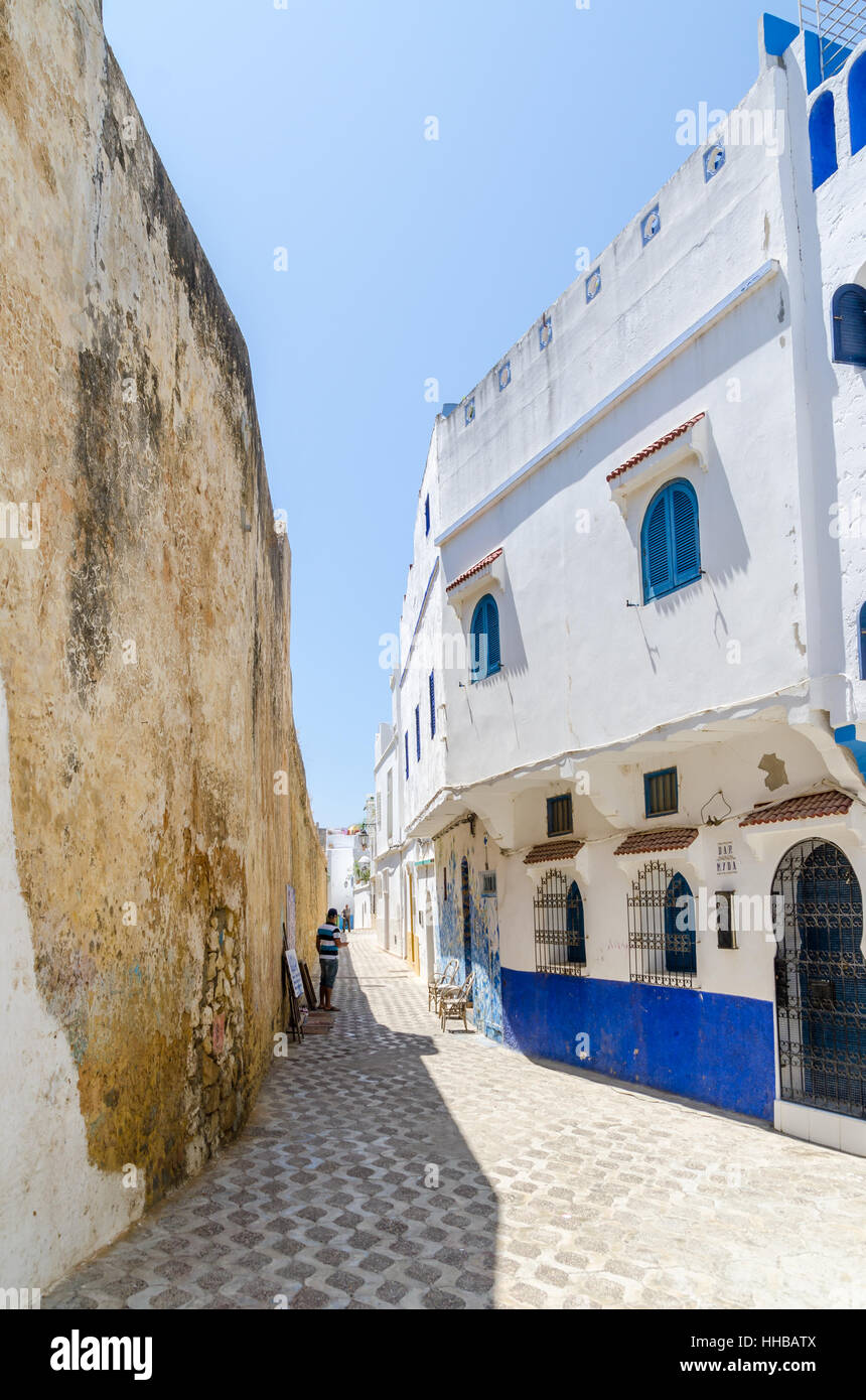 Vicolo di pietra con mura storiche della città e del blu e del bianco lavato edifici di Asilah, Marocco, Africa del Nord Foto Stock