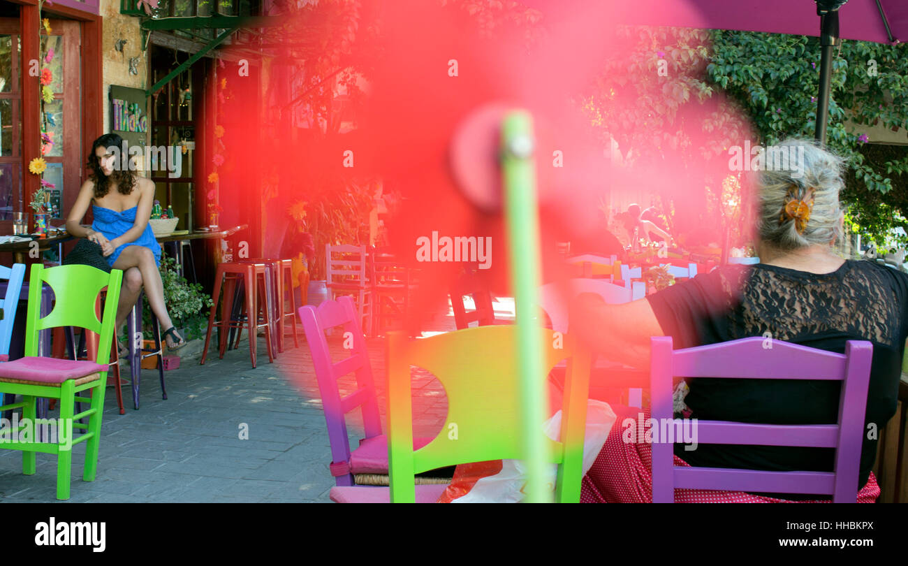 Il mulino a vento di filatura e in background, una taverna greca con gente seduta al di fuori. Foto Stock