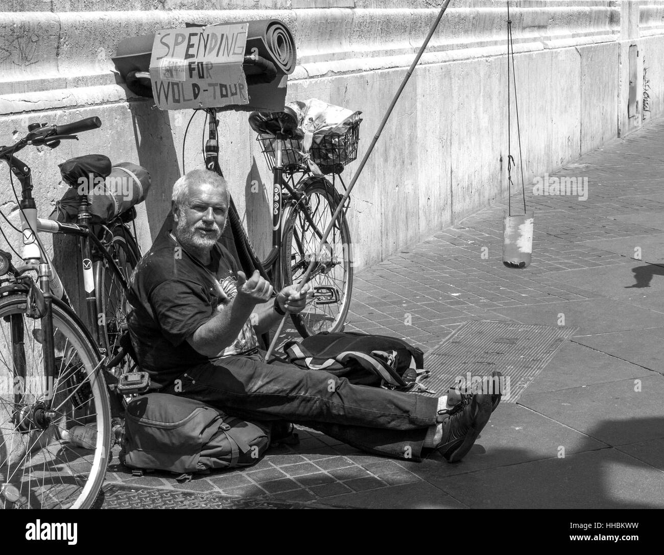 Uomo disteso sulla strada guardando la telecamera per chiedere i soldi per il suo viaggio. Foto Stock