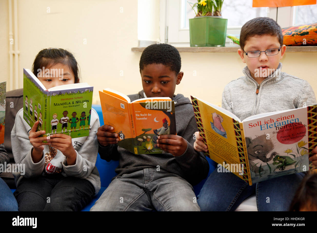 Alunni di una scuola primaria di leggere libri su live in Africa. Foto Stock