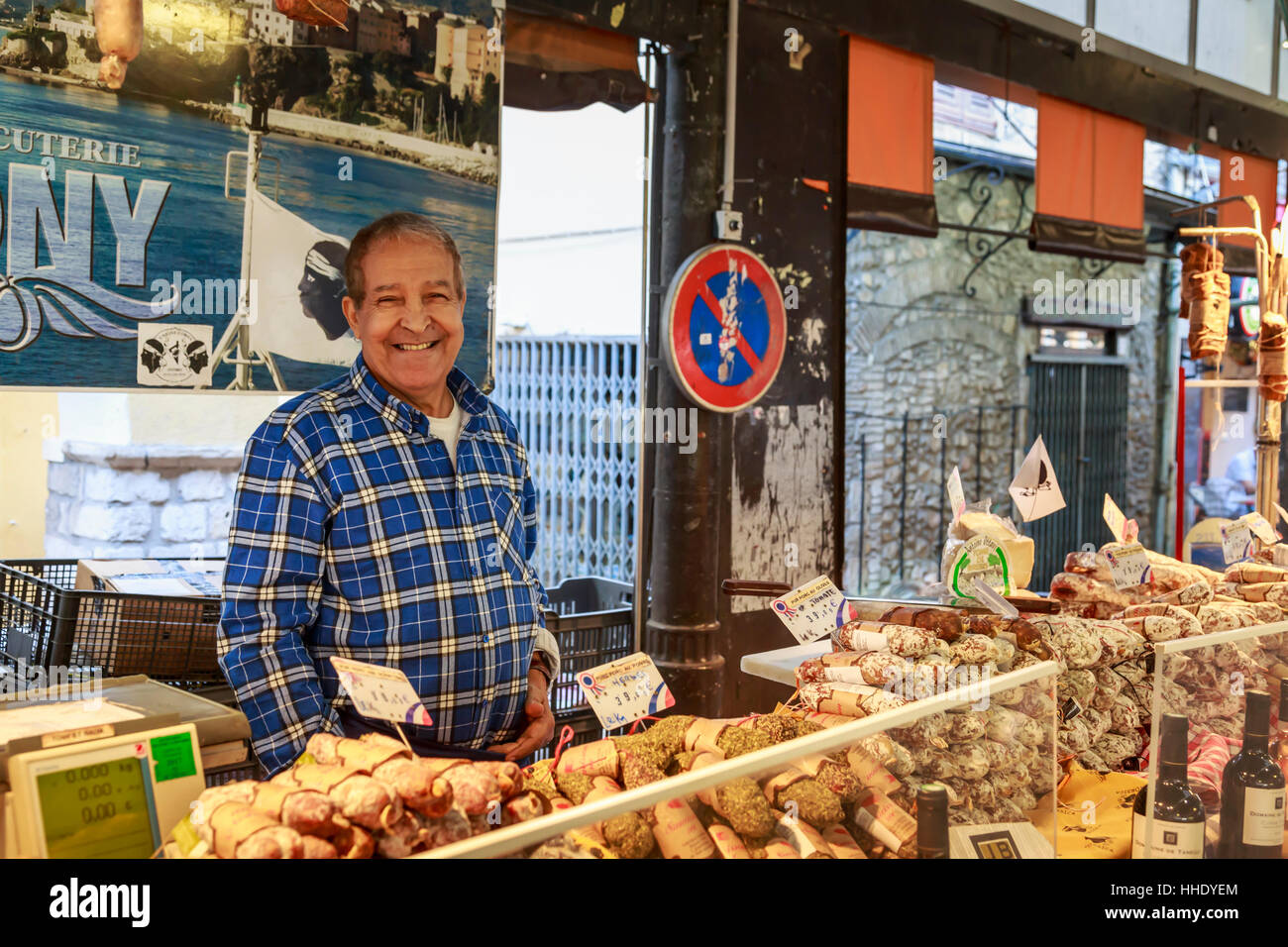 Salumi sorridente titolare di stallo, Marche provenzale, mercato mattutino, Vieil Antibes, sulla Riviera Francese, Cote d'Azur, Provenza, Francia Foto Stock